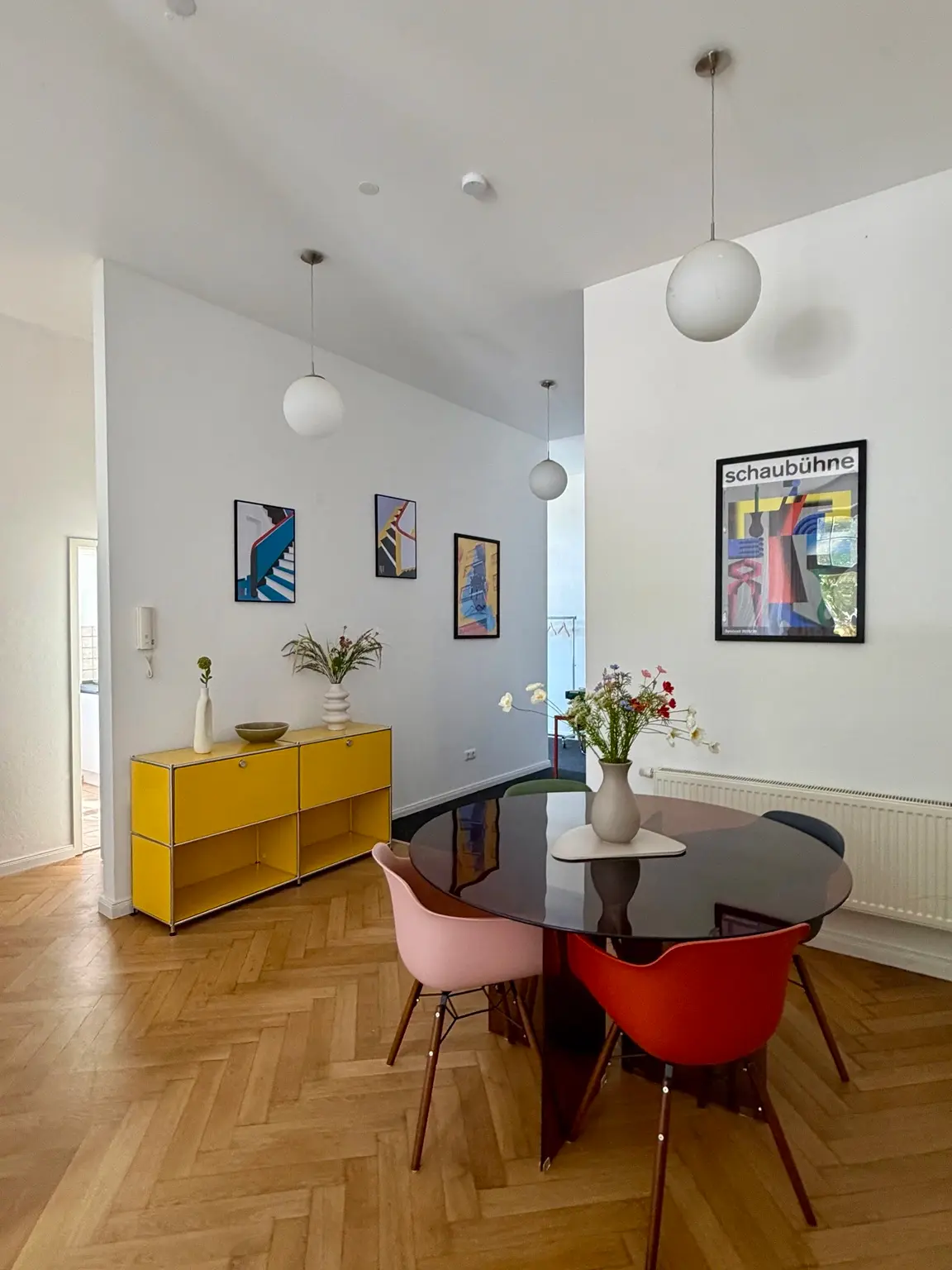 Essbereich mit rundem Tisch, farbigen Stühlen und Bauhaus Kunst