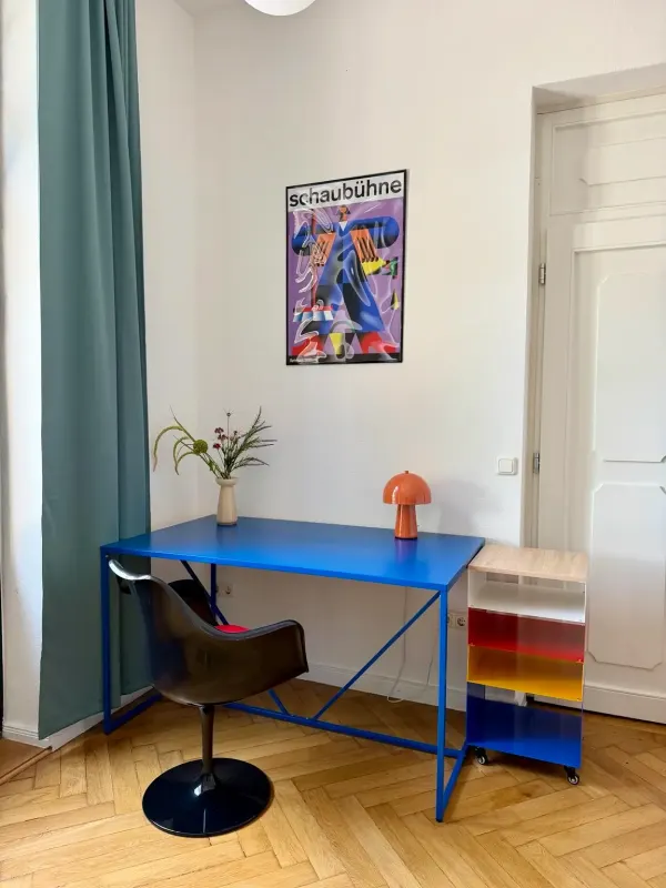 Zweiter Arbeitsplatz mit blauem Schreibtisch, Lederstuhl und Bauhaus-Poster