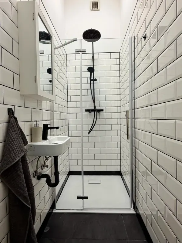 Moderne Dusche mit weißen Metrofliesen, schwarzen Armaturen und eigenem Waschtisch