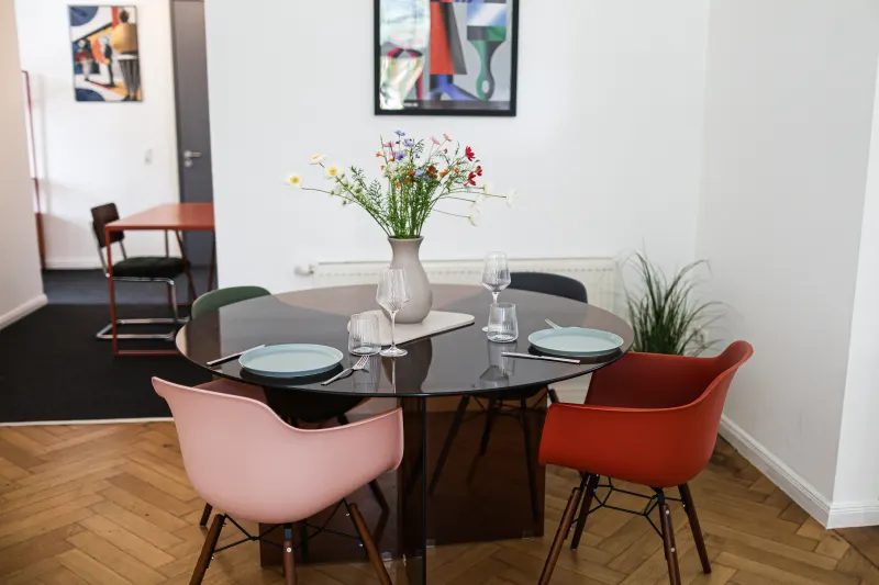 Gedeckter Esstisch mit Wildblumen, Gläsern und Tellern im Wohnraum der Ferienwohnung