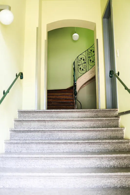 Helles Treppenhaus der Villa mit Granitstufen, grünen Wänden und geschwungenem Handlauf